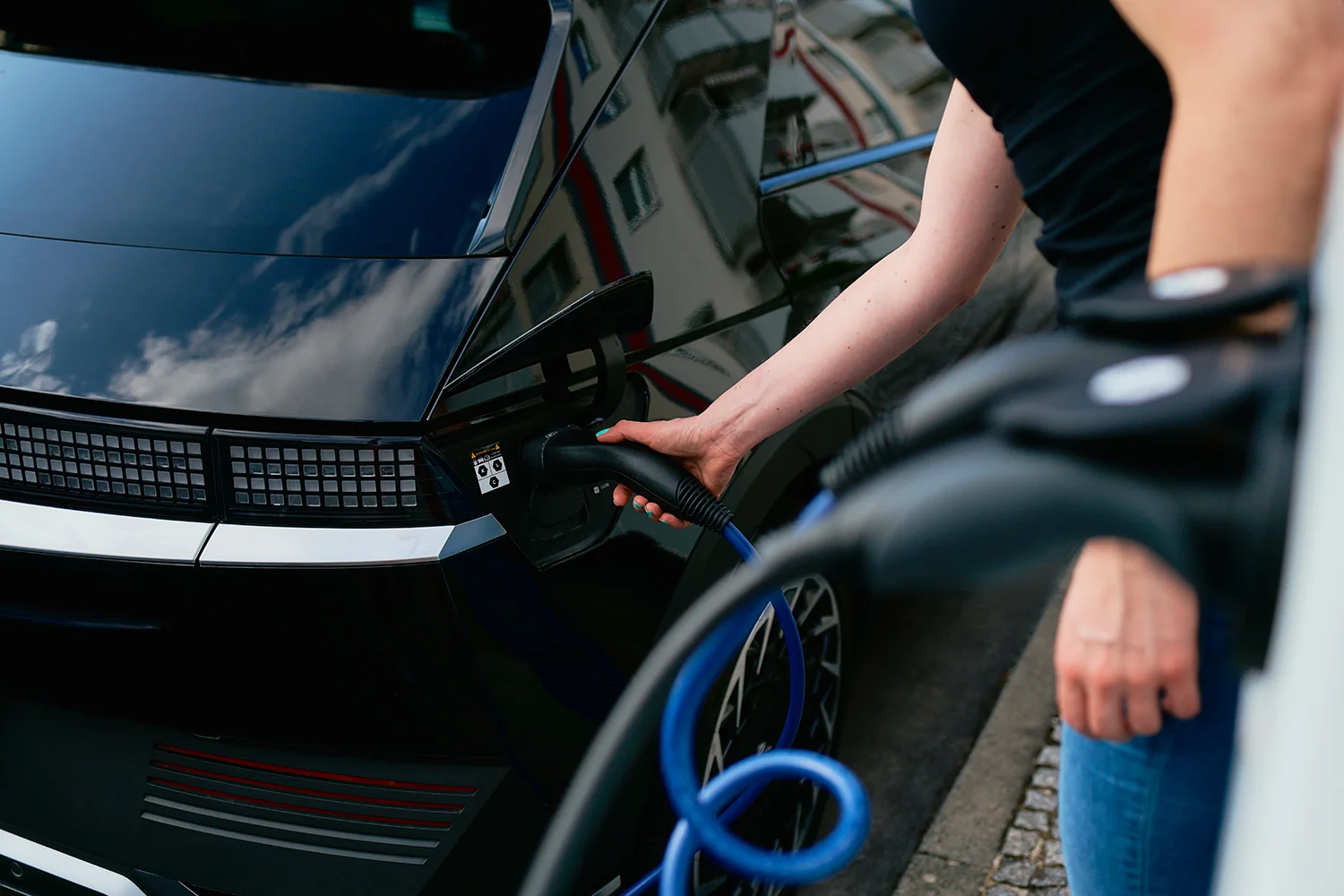 A driver of an electric vehicle is connecting her car to a public fast charger operated by ubitricity, at which she can pay with credit card, Apple Pay and Google Pay.