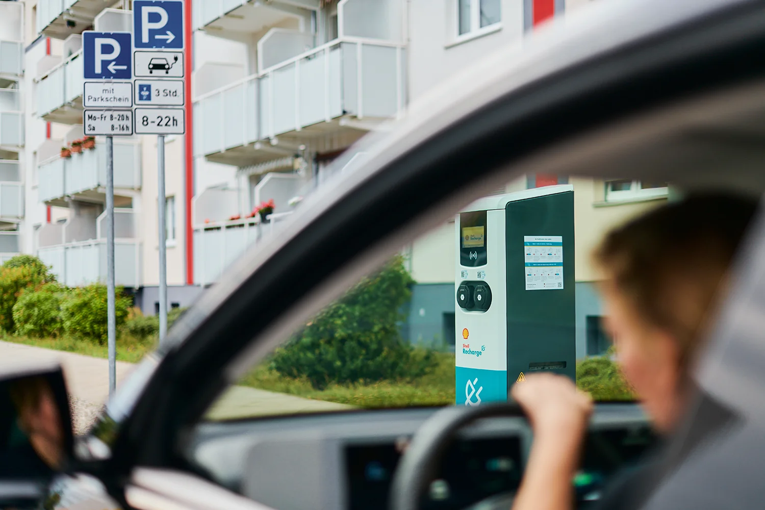 Fahrerin eines E-Autos parkt an einer öffentlichen Shell Recharge-AC-Normalladesäule, die von ubitricity betrieben wird.