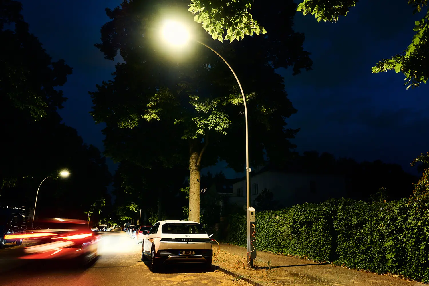 Übernachtladen eines E-Autos an einer öffentlichen ubitricity AC-Laternenladestation in einem Wohngebiet in Berlin, Deutschland