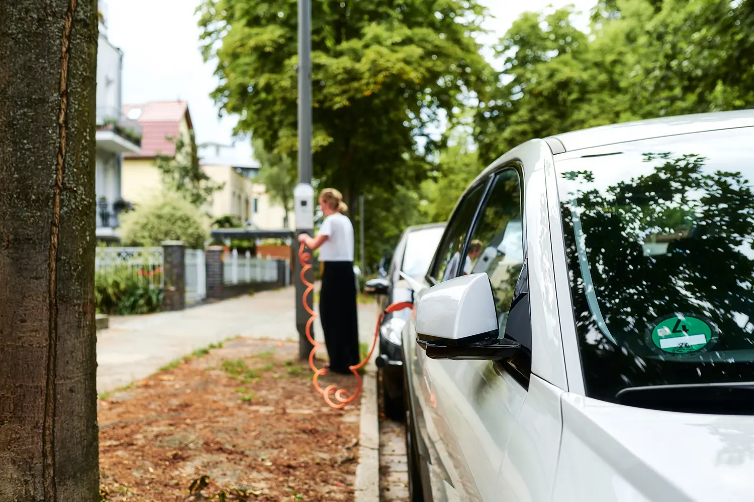 Faherin verbindet Ladekabel ihres E-Autos mit einer öffentlichen ubitricity AC-Laternenladestation in Berlin, Deutschland