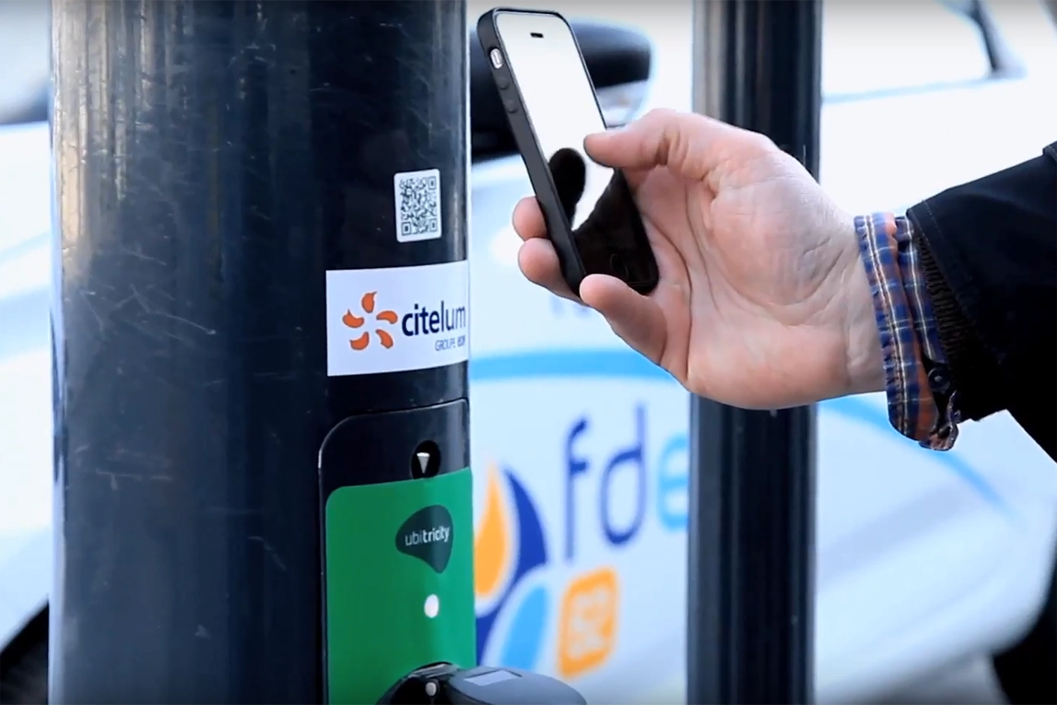 Fahrer eines E-Autos scannt QR-Code an einer öffentlichen Ladestation in Calais, Frankreich, um den Ladevorgang zu autorisieren.