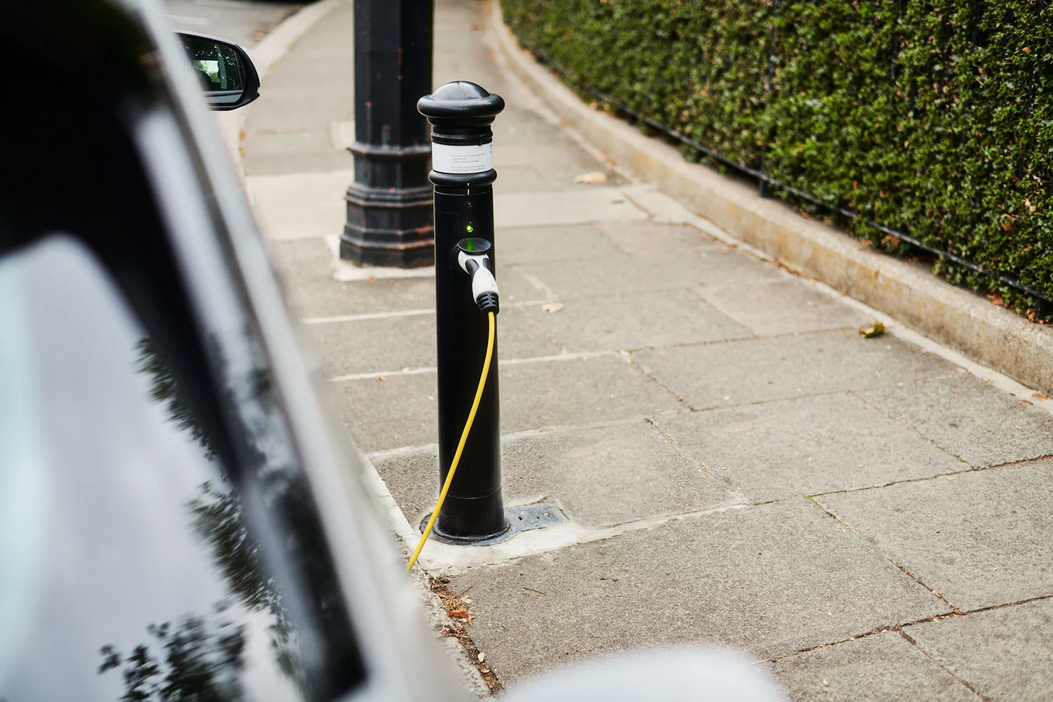 An EV is charging at an ubitricity bollard charge point, a charging solution for on street charging in residential areas.