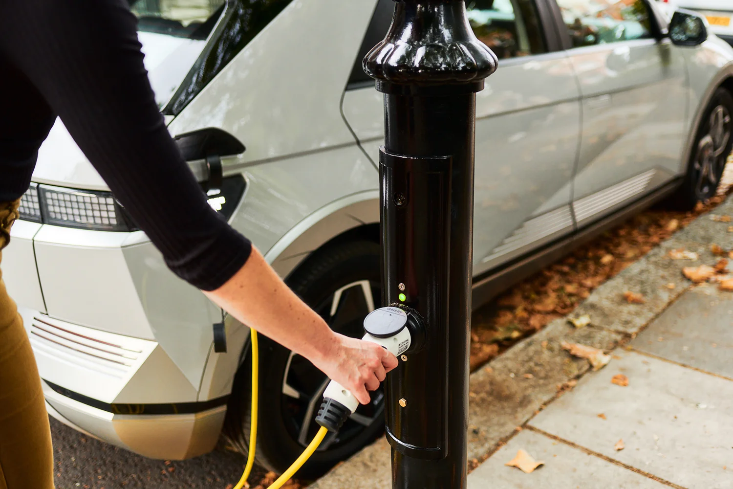 An EV driver is connecting a type 2 cable to one of ubitricity's public lamppost chargers, which can be used with pay-as-you-go, RFID charging cards and e-mobility apps.