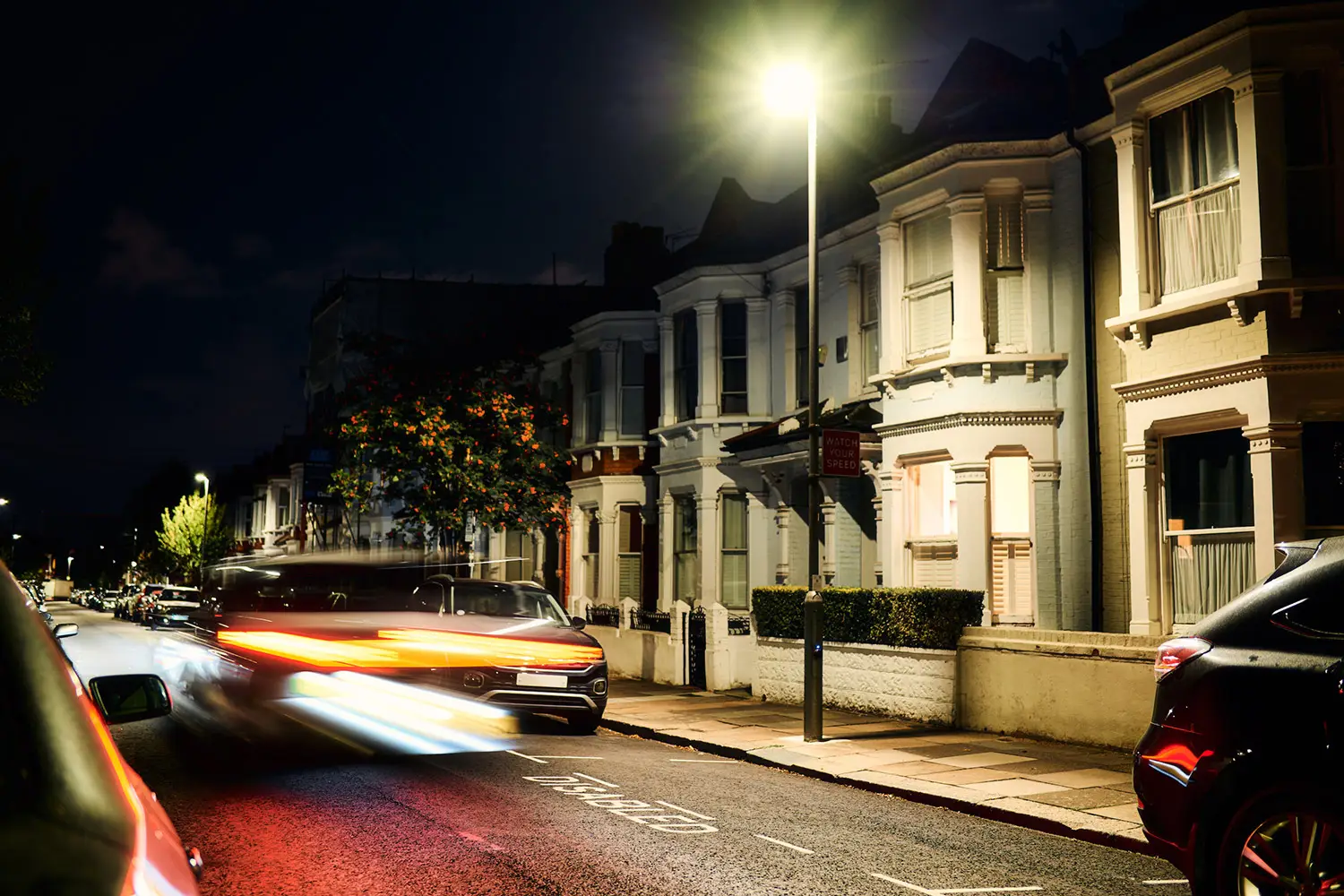 Un véhicule passe de nuit devant une station de recharge publique installée dans un lampadaire d'ubitricity au Royaume-Uni.
