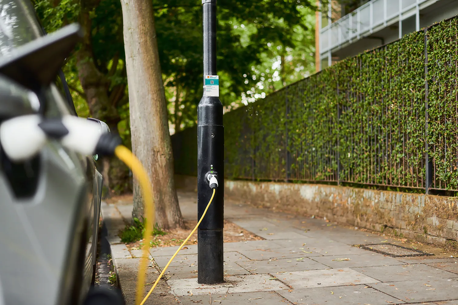 A charging cable of an EV is plugged into a Shell Recharge streetlight charger, a technology in which Shell ubitricity is a market leader in the UK in.